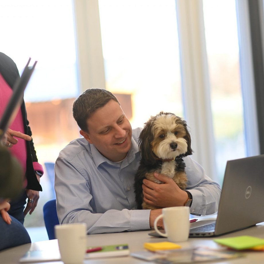 Mitarbeiter mit Hund auf dem Schoss vor dem Laptop