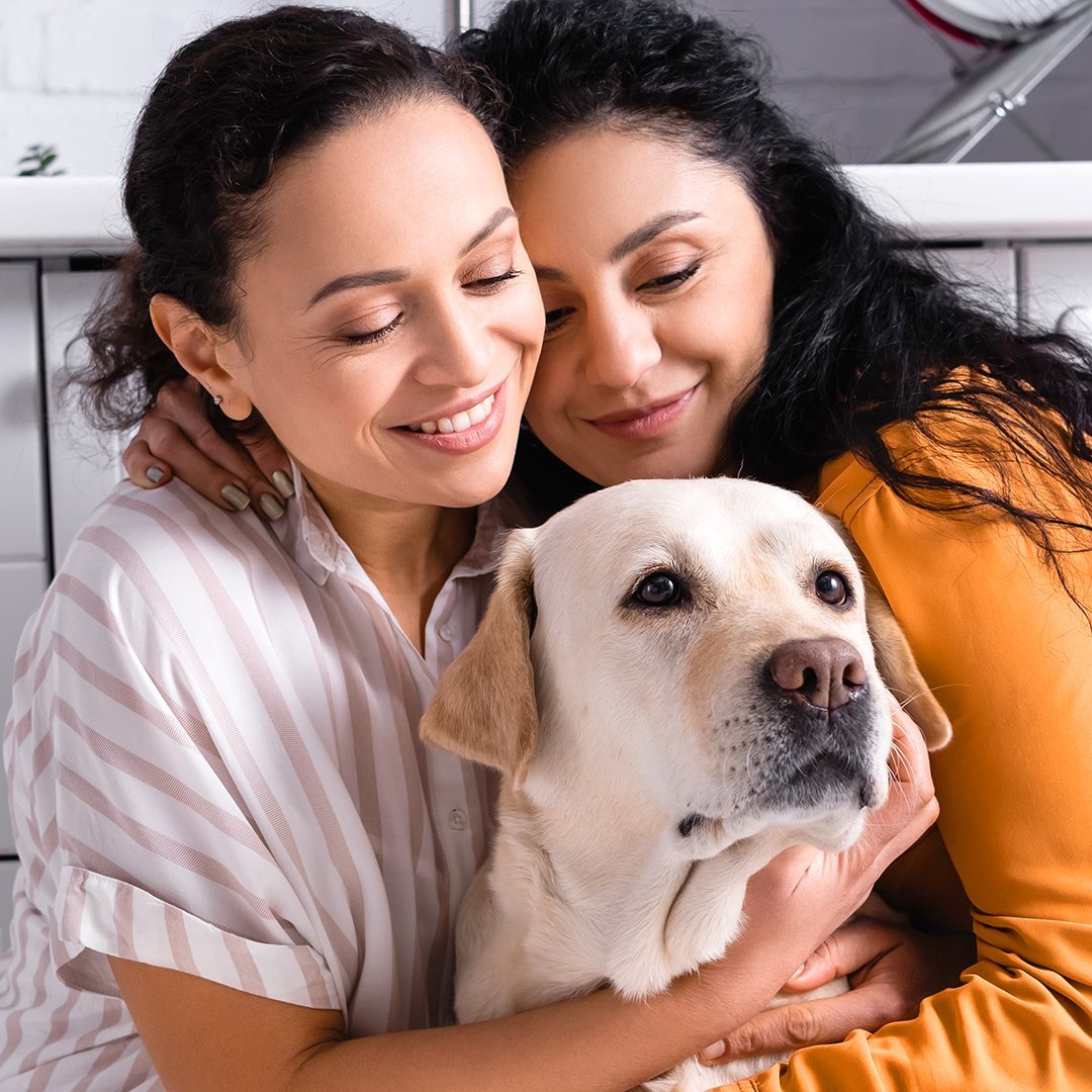 Zwei Frauen umarmen einen Hund