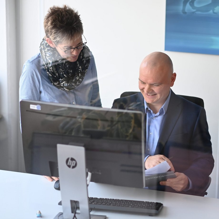 Drei Mitarbeiter vor einem PC-Arbeitsplatz