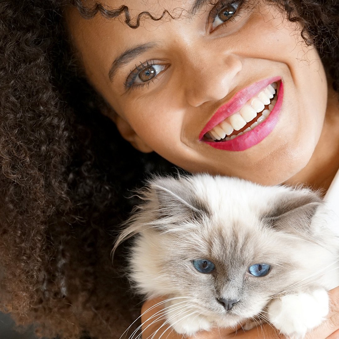 Dunkelhaarige Frau mit blauäugiger Katze im Arm