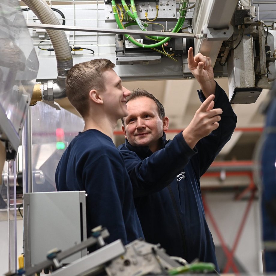 Ausbilder zeigt Auszubildenden etwas in der Produktion